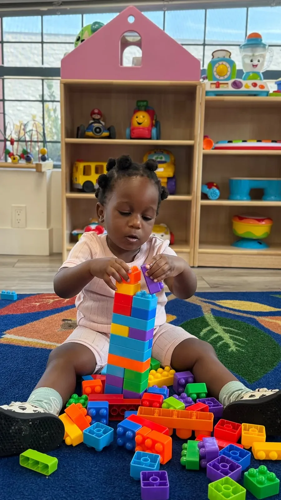 A toddler concentrating while stacking colourful building blocks into a tall tower