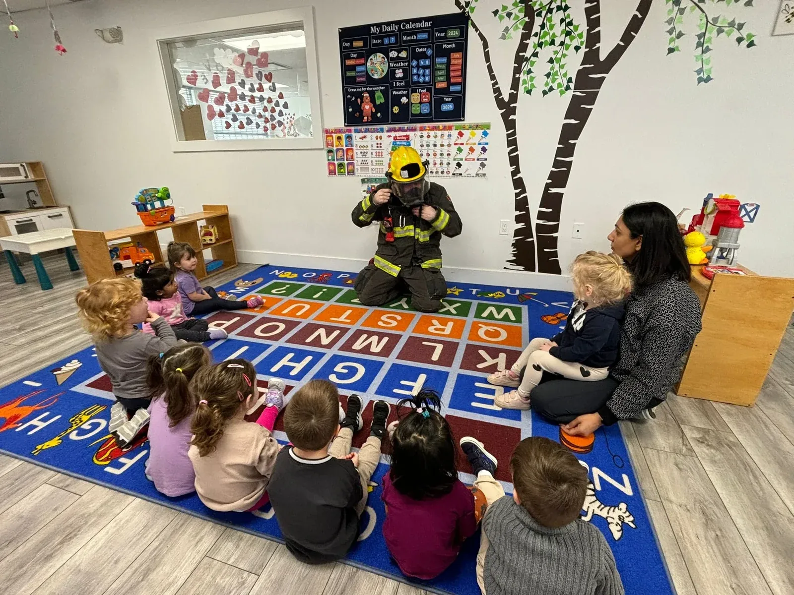 A firefighter showing children their gear during circle time on the classroom alphabet rug
