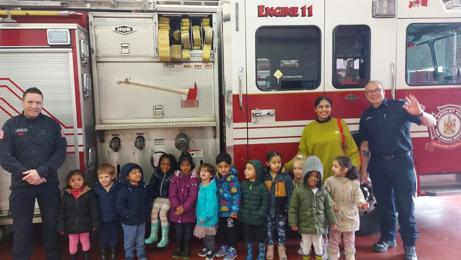 Children and educators visiting a Langley fire engine with firefighters