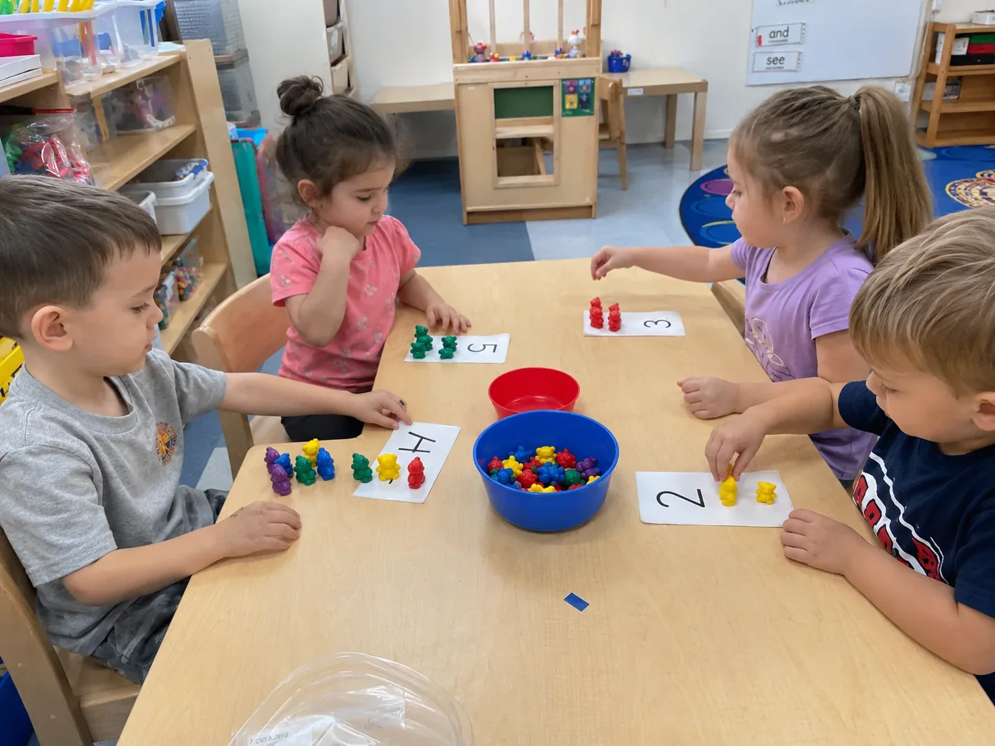 Children counting coloured bears onto number cards at a table
