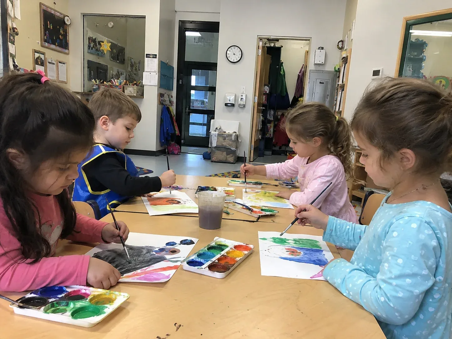 Four children painting with watercolours at a table