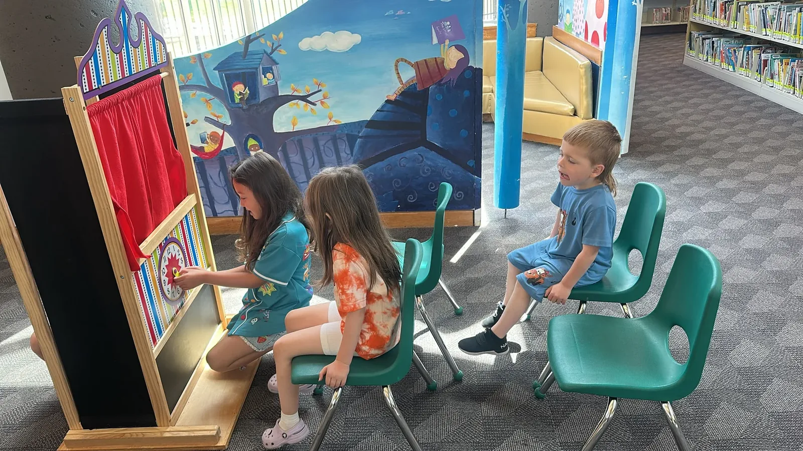 Children enjoying a puppet-theatre show in a library reading corner