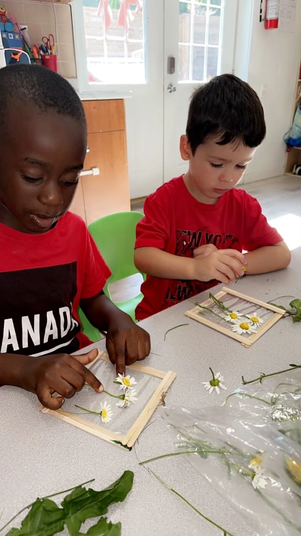Two children engaging in a hands-on literacy activity with pressed flowers and materials