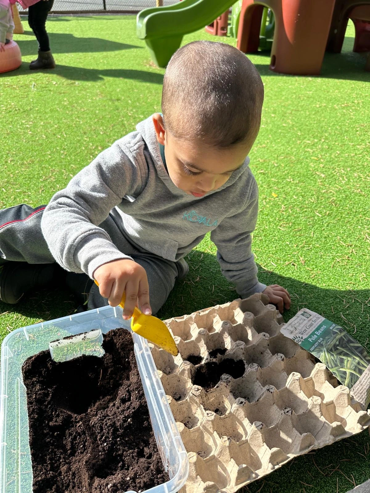 A toddler developing independence and self-help skills through sensory exploration outdoors